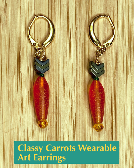 wearable art earrings shaped like carrots that have an orange root, a green stem and leaves, and gold metals. 