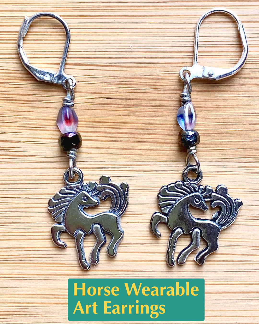 Handmade silver lever back earrings featuring a silver dancing horse charm and salvaged beads (white with blue and purple speckles and iridescent green and blue). The earrings look like dancing unicorns!