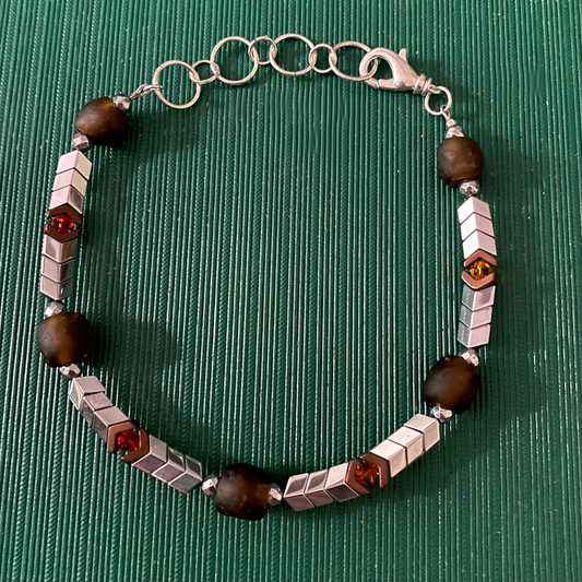 Handmade bracelet with brown and silver hematite beads, red and gray crystal beads, and brown recycled glass beads
