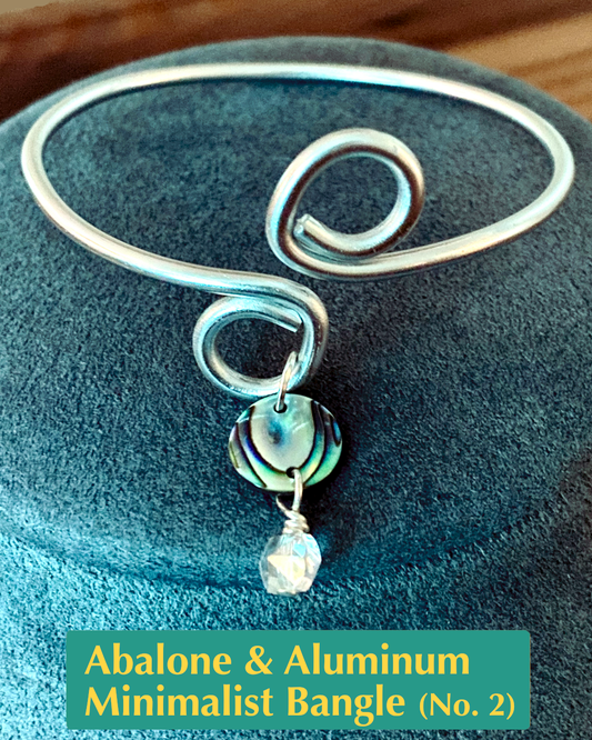 handmade silver aluminum open bangle with circle loop ends accented with an abalone shell and crystal charm