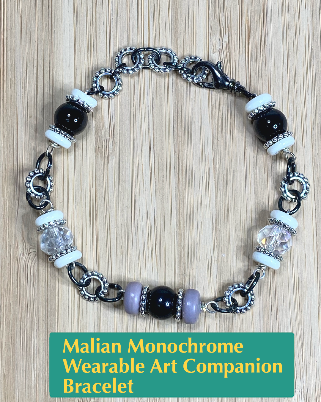 Handmade wearable art bracelet made from black onyx, white bone, clear and grey salvaged beads, and black and silver metals.