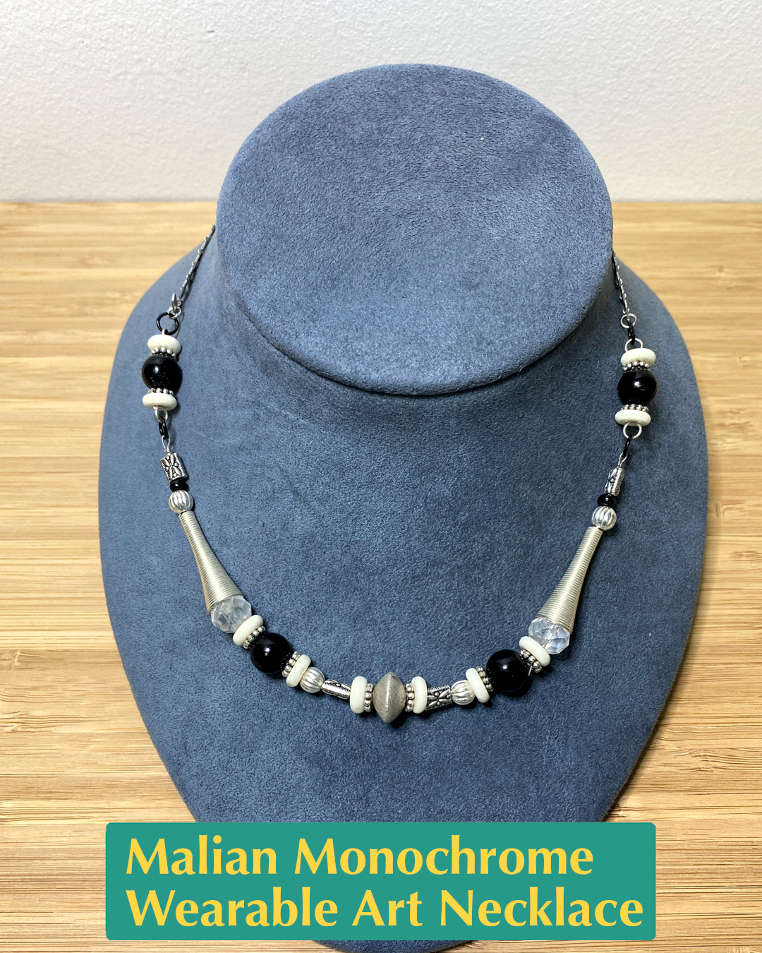 Handmade, wearable art necklace made from black and silver metals and different sized silver, black, white, and clear beads