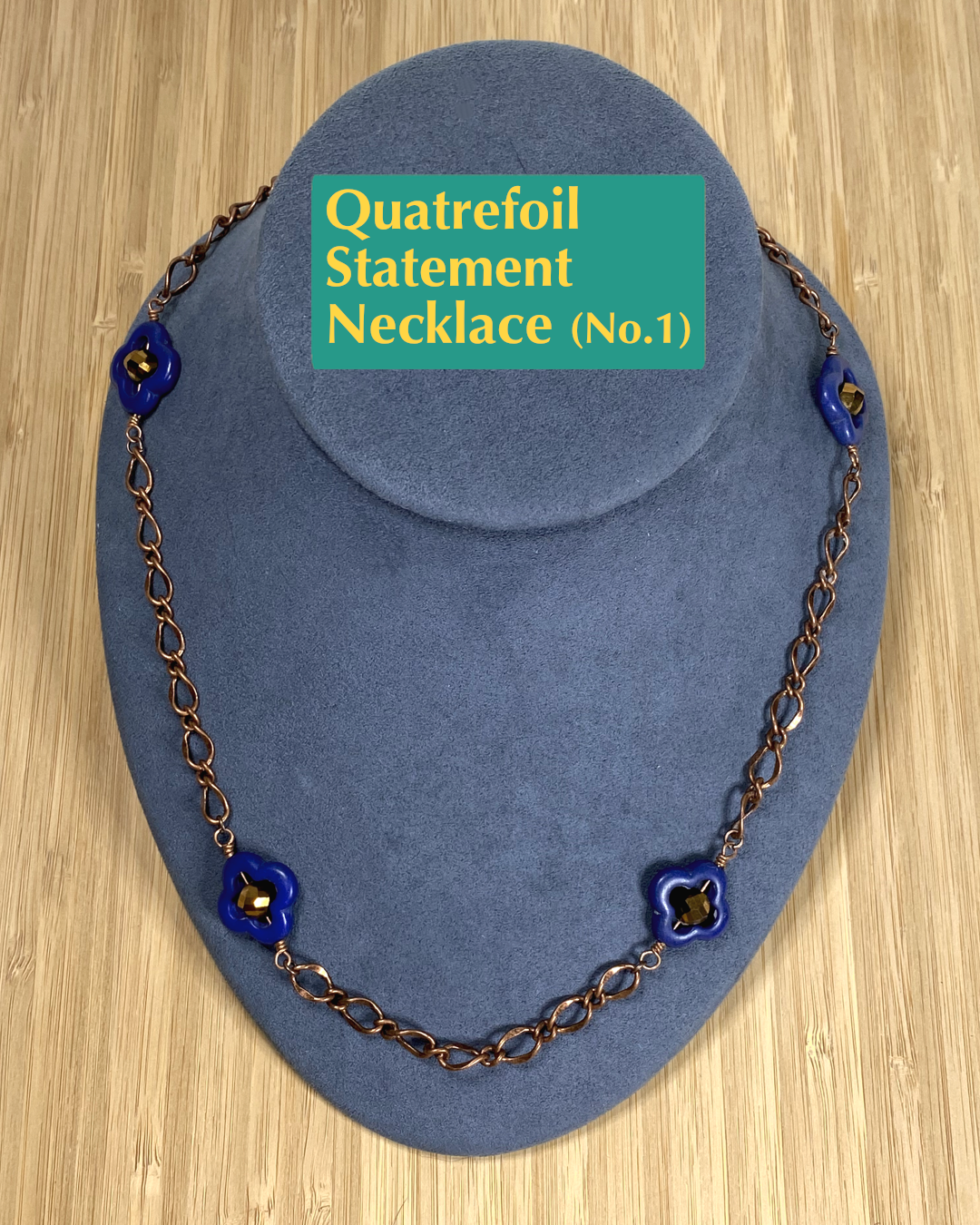 Handmade, wearable art copper necklace featuring blue and gold quatrefoil flowers with a toggle and clasp closure