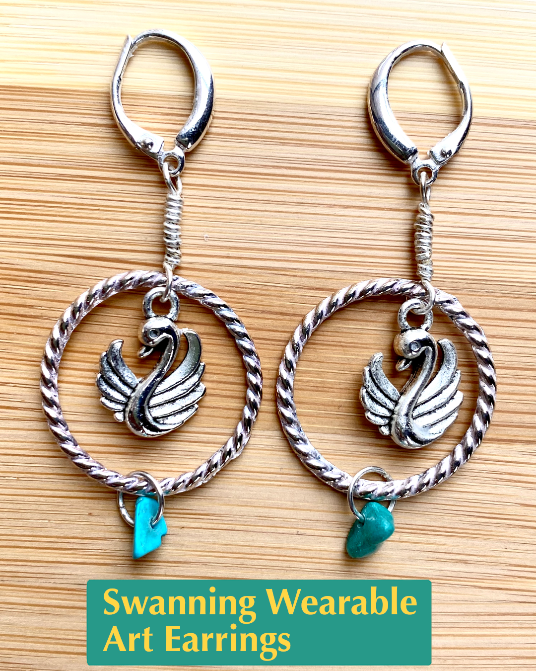 Handmade, wearable art silver hoop earrings featuring a silver swan charm and turquoise colored accent bead
