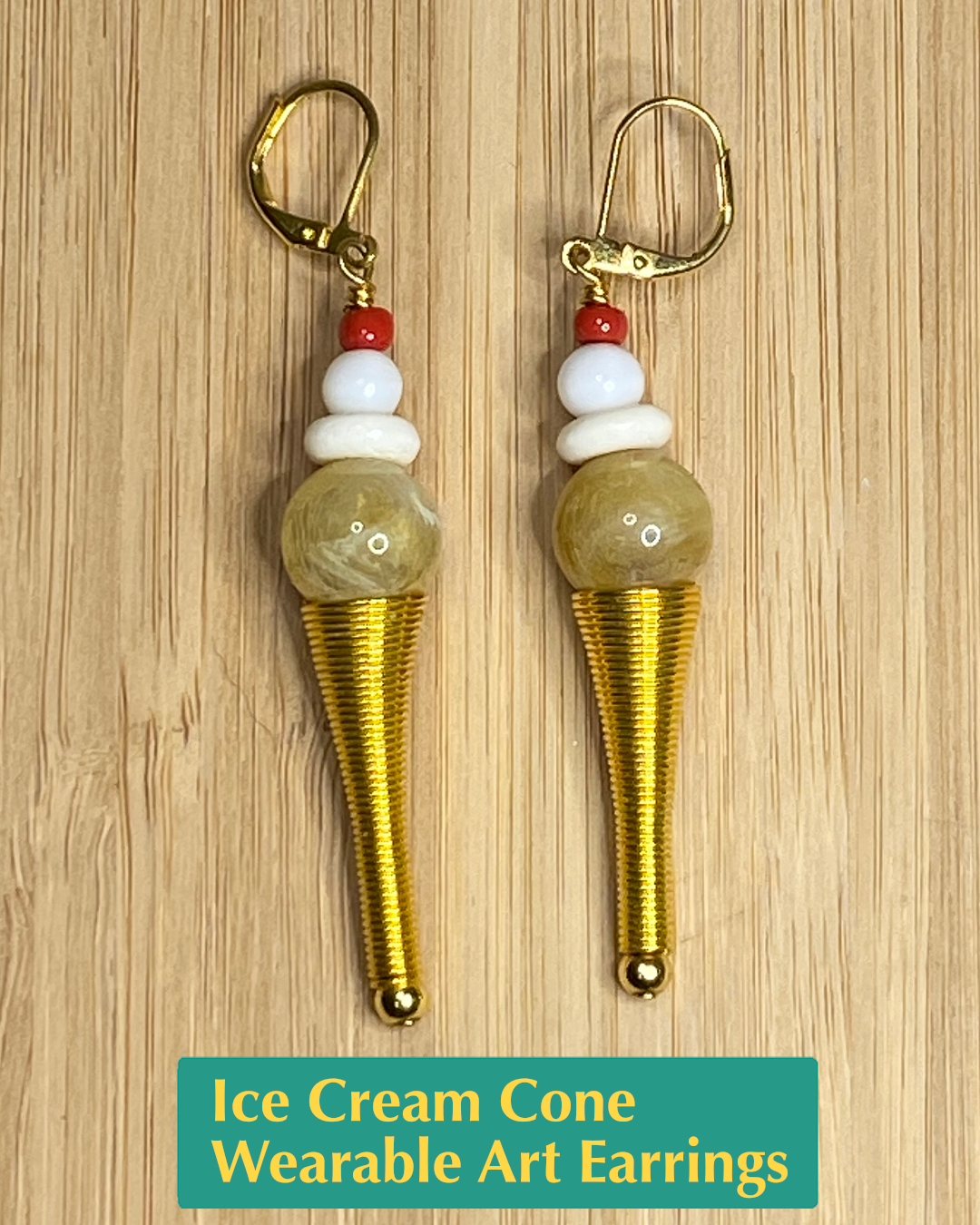 Handmade Ice cream cone shaped earrings with a gold cone, brown & white swirled ice cream scoop, whipped cream, and red cherry